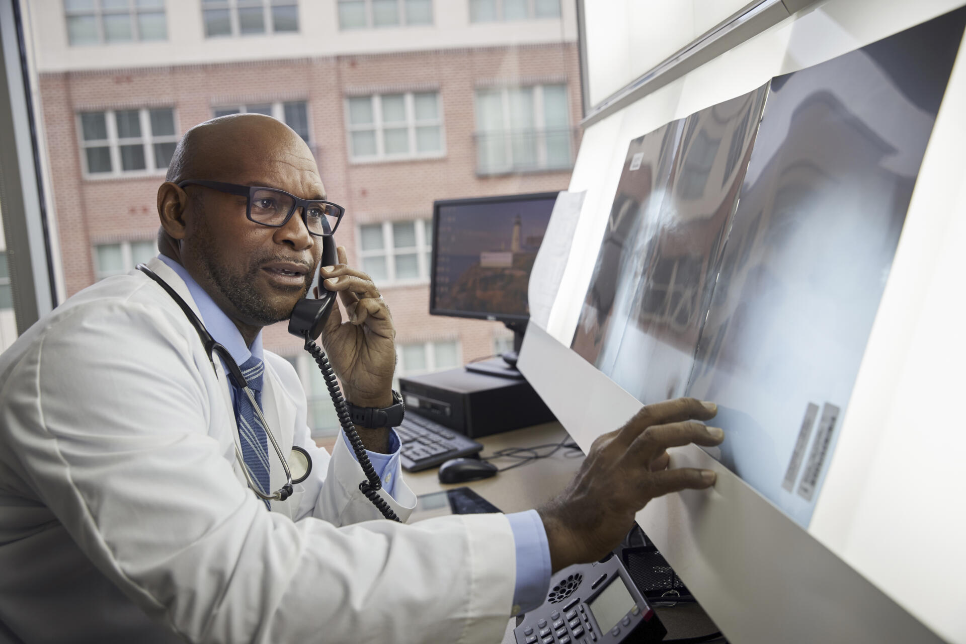 Doctor examining x ray while talking on the phone